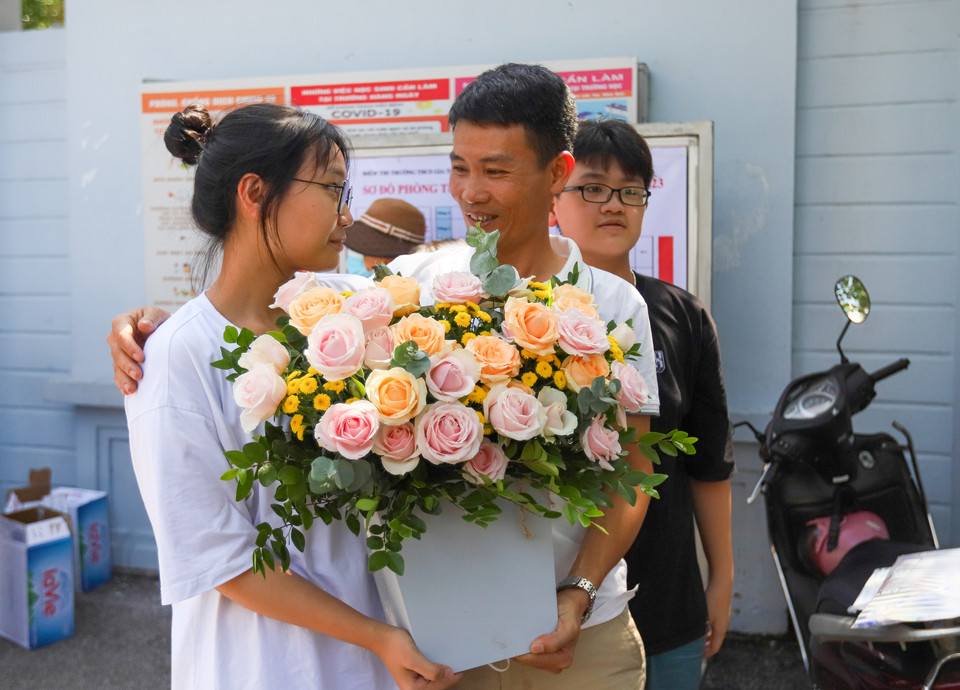 Đứng chờ ở bên ngoài, anh Phan Lý Thành (quận Long Biên) đã chuẩn bị sẵn bó hoa tươi thắm để tặng cho con gái. “Khi thấy con chia sẻ làm được bài tôi vui lắm. Dù kết quả thi có thế nào thì tôi cũng muốn dành bó hoa này để động viên, khích lệ tinh thần cho con. Gia đình luôn ở bên con,” anh Thành mừng rỡ chia sẻ. (Ảnh: PV/Vietnam+)