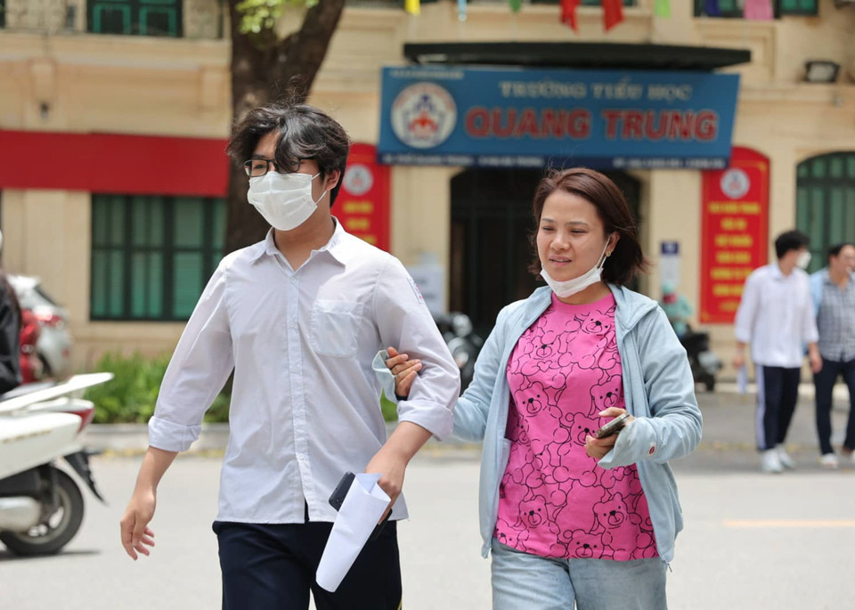 Một số phụ huynh dắt tay thí sinh vào điểm thi. (Ảnh: PV/Vietnam+) 