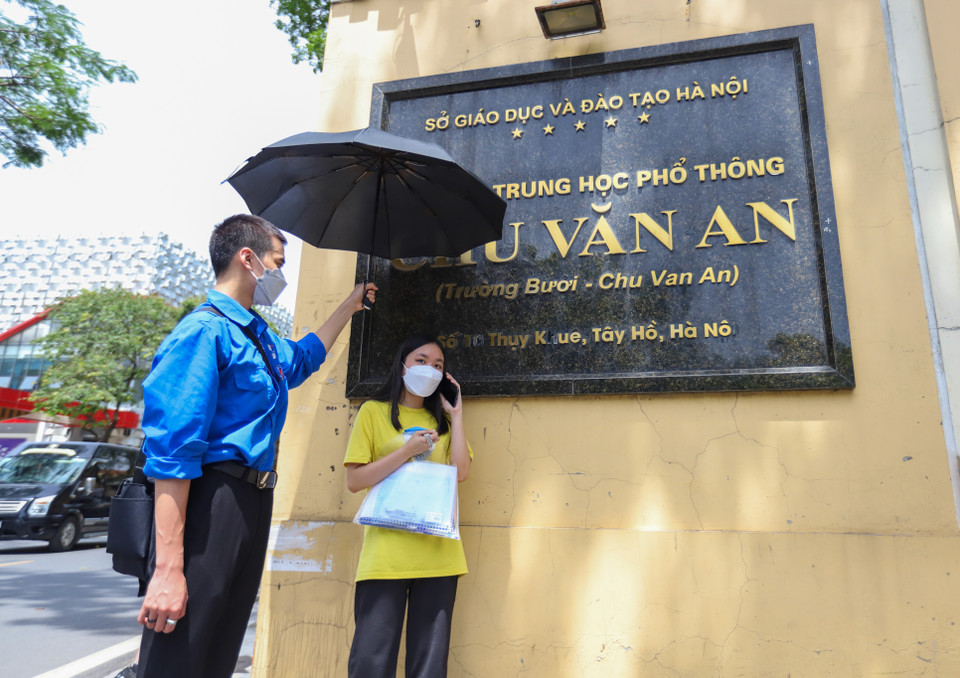 Trong buổi thi với thời tiết nắng, nóng cao điểm như hôm nay, các bạn tình nguyện viên trường Đại học Giao thông vận tải sẵn sàng ô che nắng đón thí sinh khi vào và ra tại điểm thi THPT Chu Văn An (quận Tây Hồ). (Ảnh: PV/Vietnam+)