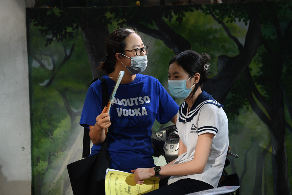 Một phụ huynh quạt mát cho thí sinh. (Ảnh: PV/Vietnam+) 