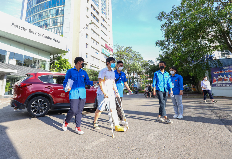 Tại điểm thi này, có 2 thí sinh không may bị gãy chân phải chống nạng đi thi. Thí sinh được đội thanh niên tình nguyện hỗ trợ cầm đồ và đưa vào phòng thi. (Ảnh: PV/Vietnam+)