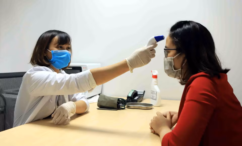 Đo nhiệt độ cho công nhân tại phòng y tế Công ty TNHH sản xuất hàng may mặc Việt Nam (TAL), khu công nghiệp Bá Thiện 2 (huyện Bình Xuyên). (Ảnh: Hoàng Hùng/TTXVN)
