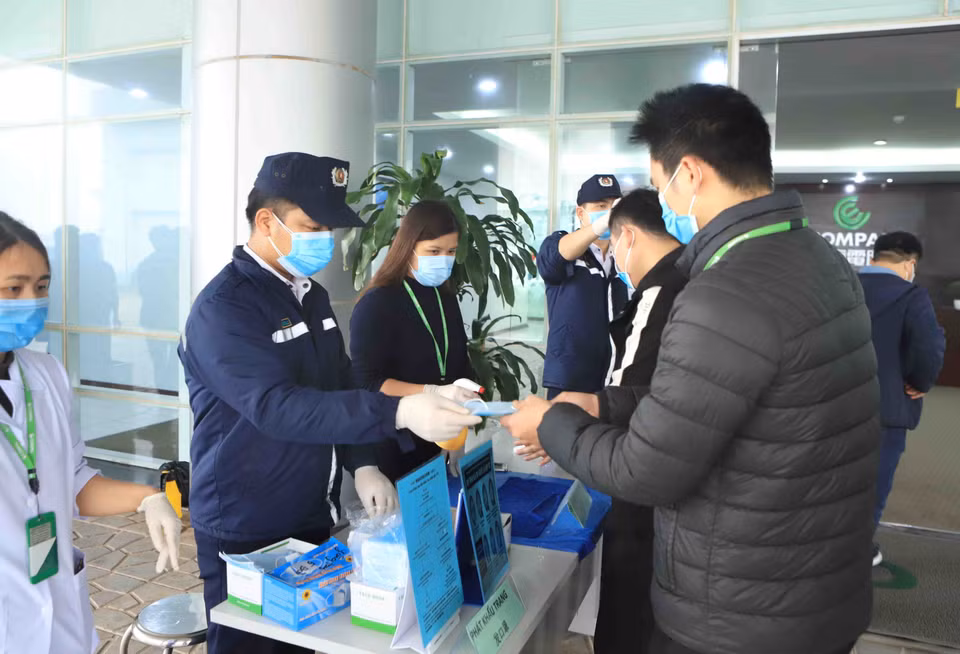 Công ty TNHH Compal Việt Nam trong khu công nghiệp Bá Thiện 1 (huyện Bình Xuyên) phát khẩu trang mới cho cán bộ, công nhân trước khi vào làm việc. (Ảnh: Hoàng Hùng/TTXVN)