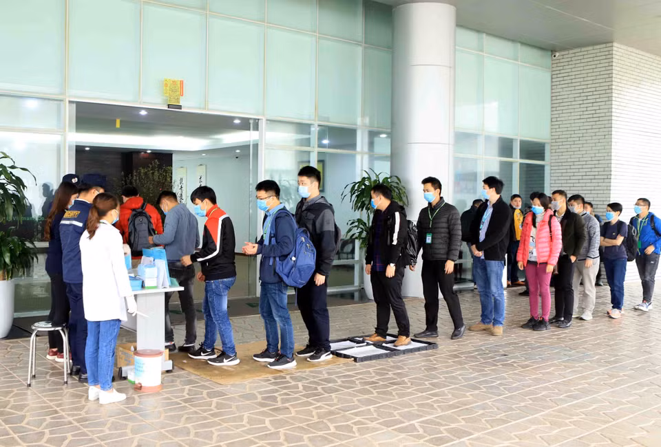Tất cả công nhân, cán bộ, khách hàng đến làm việc tại Công ty TNHH Compal Việt Nam trong khu công nghiệp Bá Thiện 1 (huyện Bình Xuyên) đều đeo khẩu trang mới, đi qua khay dung dịch khử khuẩn, sát khuẩn tay và đo nhiệt độ để phòng chống dịch COVID-19. (Ảnh: Hoàng Hùng/TTXVN)