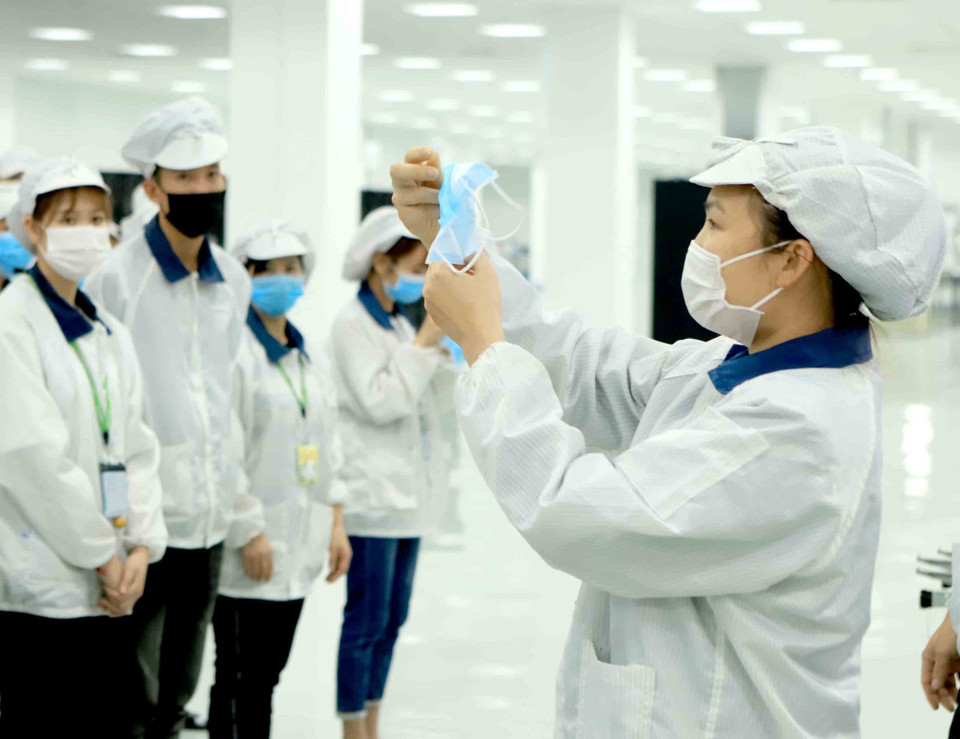 Công ty TNHH Compal Việt Nam trong khu công nghiệp Bá Thiện 1 (huyện Bình Xuyên) hướng dẫn cho công nhân đeo khẩu trang đúng cách để phòng chống dịch COVID-19. (Ảnh: Hoàng Hùng/TTXVN)