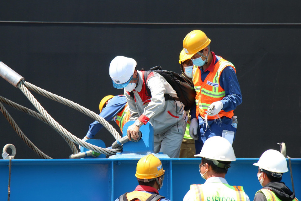 Các chuyên gia, công nhân thực hiện nối cáp vào khung để cẩu toa xe khỏi tàu vận chuyển Pulang Tala. (Ảnh: Tiến Lực/TTXVN)