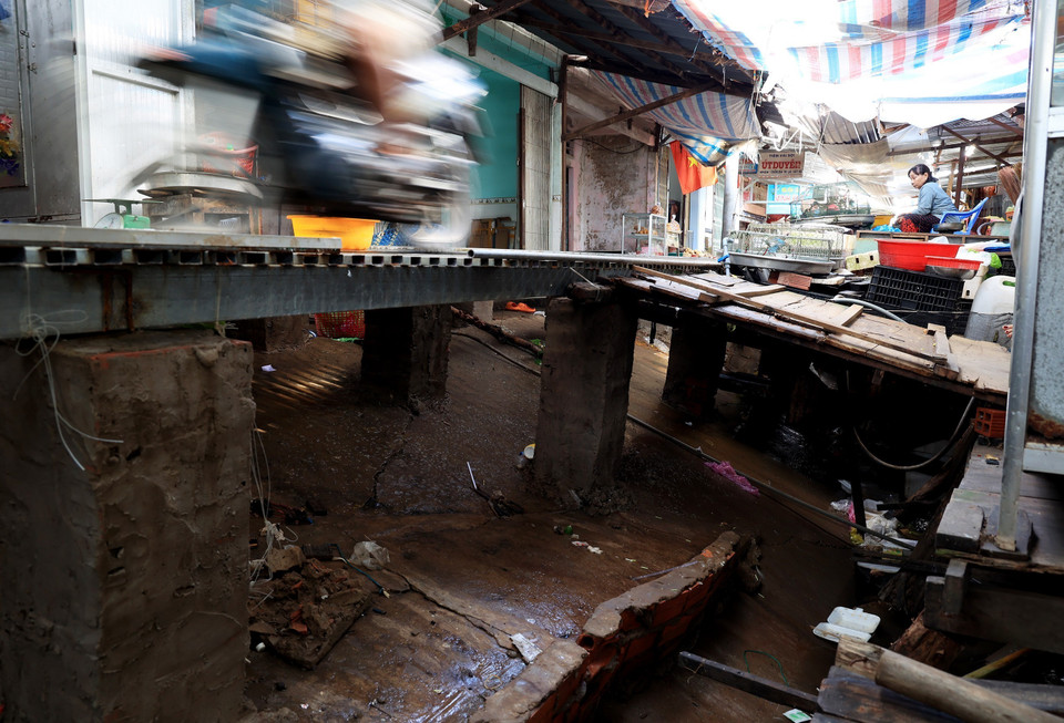 Cây cầu sắt tạm thay con đường bị sạt lở, sụt lún chạy trong chợ Tân Tiến, gặp trời mưa trơn trượt khiến nhiều xe máy, người dân đi lại bị té ngã. (Ảnh: Hồng Đạt/TTXVN) 