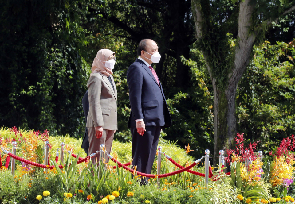 Chủ tịch nước Nguyễn Xuân Phúc và Tổng thống Cộng hòa Singapore Halimah Yacob nghe quân nhạc cử Quốc thiều hai nước. (Ảnh: Thống Nhất/TTXVN)