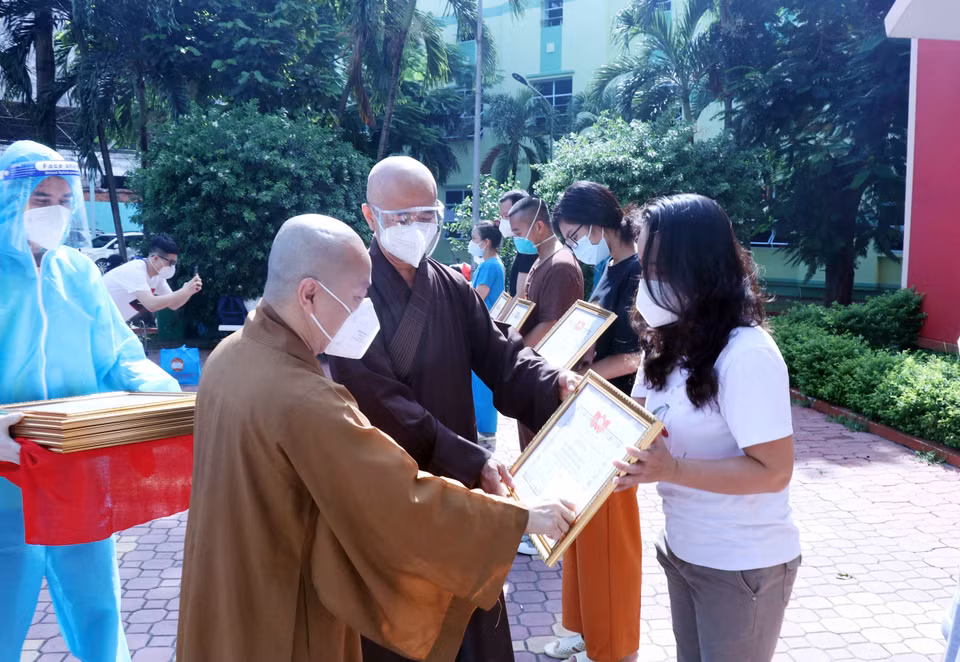 Thượng tọa Thích Thiện Quý, Phó Trưởng ban kiêm Chánh Thư ký Ban Trị sự Giáo hội Phật giáo Việt Nam Thành phố Hồ Chí Minh và Thượng tọa Thích Nhật Từ, Phó Viện trưởng Thường trực Học viện Phật giáo Việt Nam tại Thành phố Hồ Chí Minh trao giấy biểu dương và tặng quà cho các tình nguyện viên tôn giáo. (Ảnh: Xuân Khu/TTXVN)