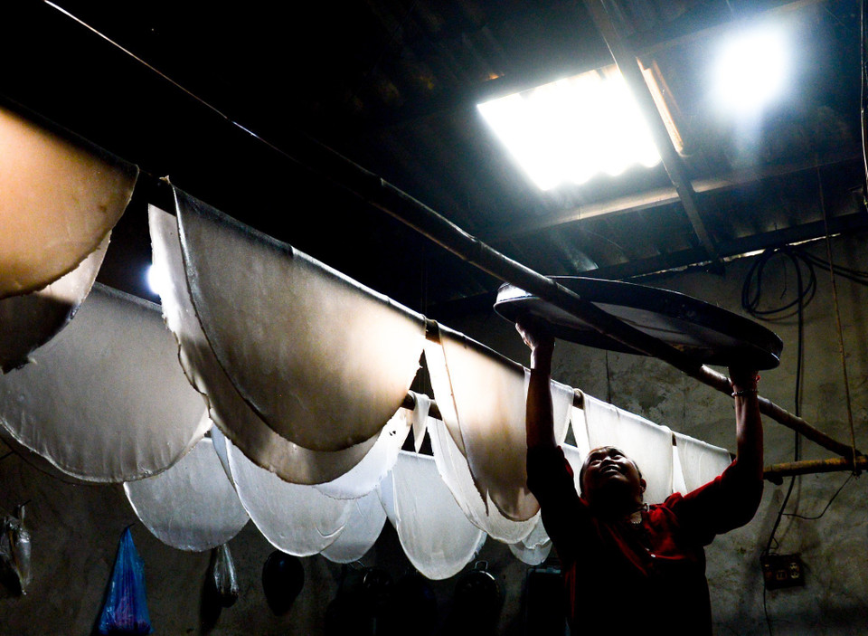 Bà con đổ bột vào khuôn tráng lớn, sau đó thả trực tiếp vào nồi nước sôi để hấp chín, sau khoảng 7-10 phút, bánh phở được lấy ra khỏi khuôn và phơi trên các sào tre. (Ảnh: Nam Thái/TTXVN)