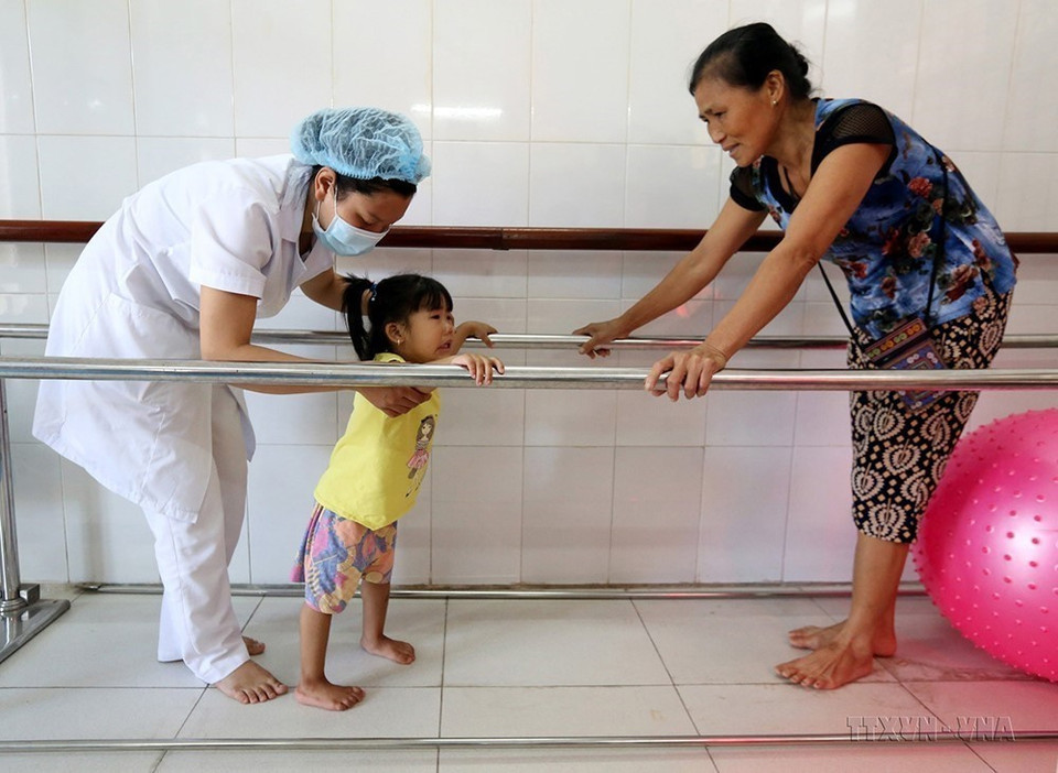 Kỹ thuật viên tập phục hội chức năng cho trẻ bị khuyết tật vận động tại Bệnh viện Chỉnh hình và phục hồi chức năng Hà Nội. (Ảnh: Anh Tuấn/TTXVN)