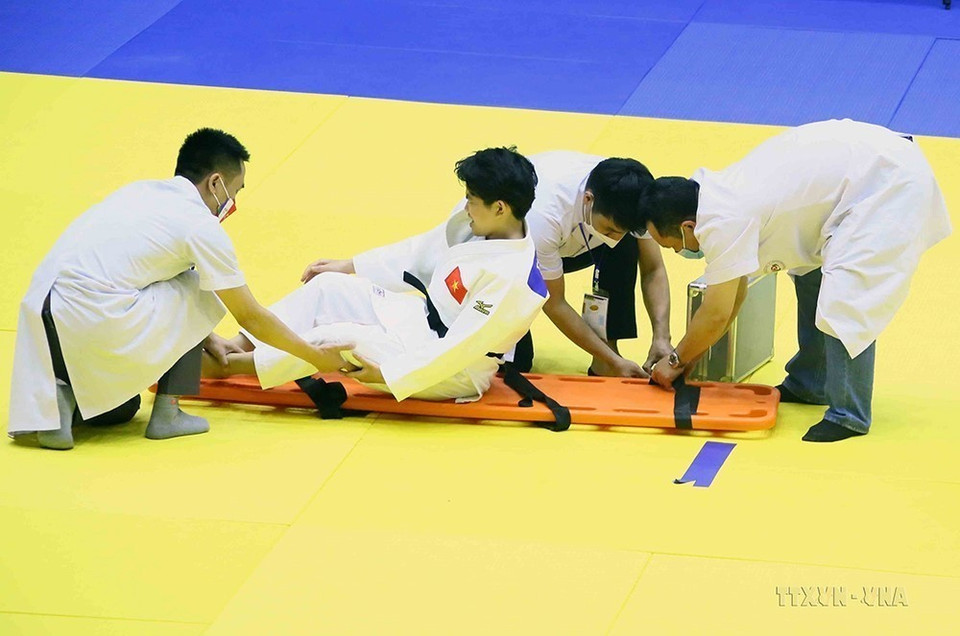 Các nhân viên y tế chăm sóc vận động viên Karate Trần Lê Phương Nga gặp chấn thương nặng trong thi đấu ở SEA Games 31 (18/5/2022). (Ảnh: Quang Quyết/TTXVN)