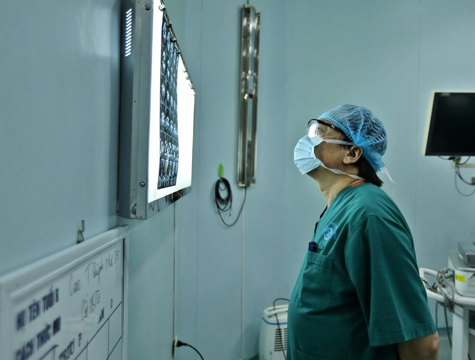 Phó Giáo sư, Tiến sỹ Trần Ngọc Lương đọc phim chụp của bệnh nhân trước khi phẫu thuật. (Ảnh: Minh Quyết/TTXVN)