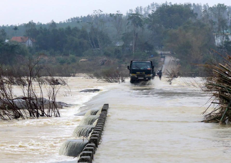 Người dân điều khiển phương tiện vượt dòng nước chảy xiết. (Ảnh: Lê Ngọc Phước/TTXVN)