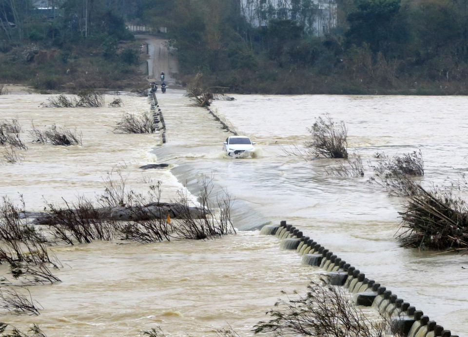 Người dân điều khiển phương tiện vượt dòng nước chảy xiết. (Ảnh: Lê Ngọc Phước/TTXVN)