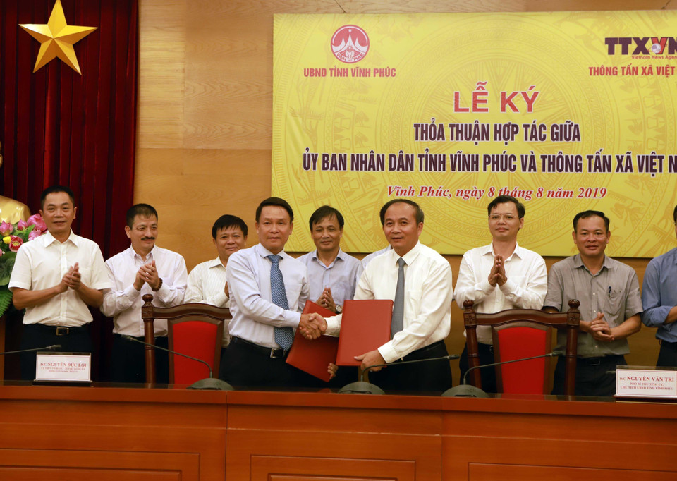 Tổng Giám đốc Thông tấn xã Việt Nam Nguyễn Đức Lợi (trái) và Phó Bí thư Tỉnh ủy, Chủ tịch UBND tỉnh Vĩnh Phúc Nguyễn Văn Trì ký thỏa thuận hợp tác. (Ảnh: Hoàng Hùng/TTXVN)