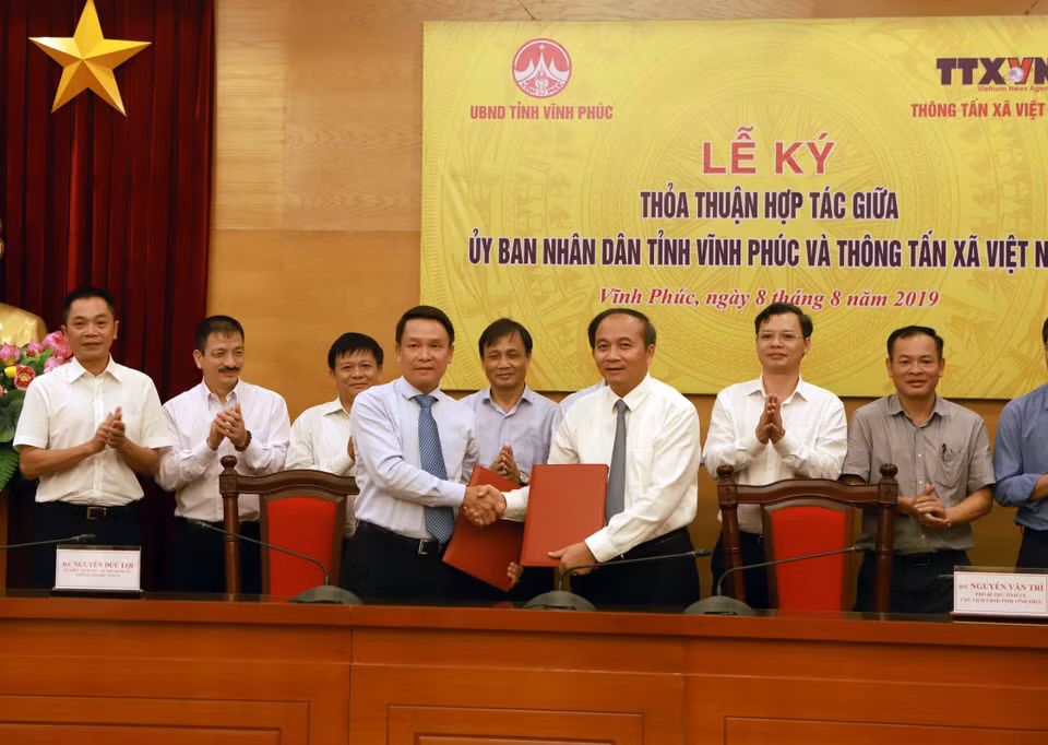 Tổng Giám đốc Thông tấn xã Việt Nam Nguyễn Đức Lợi (trái) và Phó Bí thư Tỉnh ủy, Chủ tịch UBND tỉnh Vĩnh Phúc Nguyễn Văn Trì ký thỏa thuận hợp tác. (Ảnh: Hoàng Hùng/TTXVN)