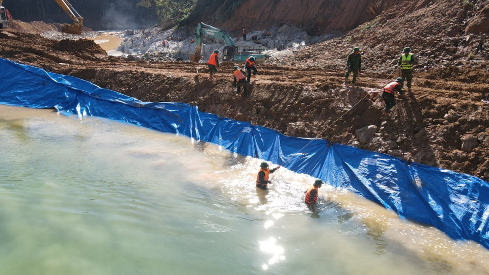 Lực lượng chức năng nắm dòng chảy mới được tạo nên để phục vụ công tác tìm kiếm dưới lòng suối Rào Trăng. (Ảnh: TTXVN phát)