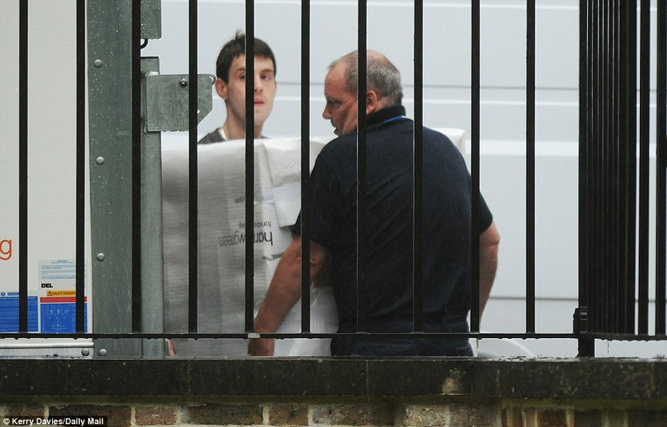 Công nhân mang vác đồ đạc ra khỏi tòa nhà. (Nguồn: Dailymail)