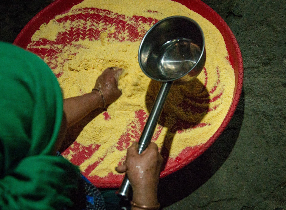 Ngô được xay nhiều lần cho đến khi trở thành bột mịn vừa ý, đổ bột vào nia, trộn cùng một chút nước. (Ảnh: Nam Thái/TTXVN)