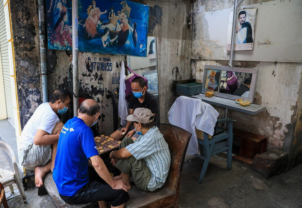 Các cụ già đeo khẩu trang đánh cờ đầu con ngõ nhỏ trên đường Bạch Đằng. (Ảnh: Thành Đạt/TTXVN)