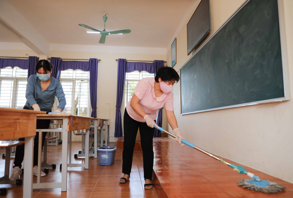 Giáo viên trường THCS Chàng Sơn, huyện Thạch Thất vệ sinh lớp học chuẩn bị đón học sinh trở lại trường. (Ảnh: Thanh Tùng/TTXVN)