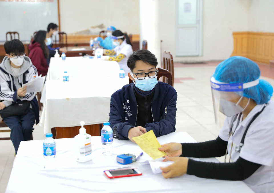 Nhân viên y tế khám sàng lọc trước khi tiêm mũi 2 vaccine phòng COVID-19 cho học sinh trường THPT Việt Đức. (Ảnh: Thanh Tùng/TTXVN)