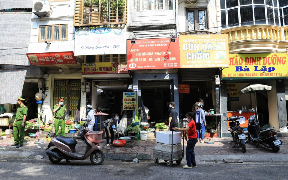 Lực lượng công an phường Quốc Tử Giám, quận Động Đa nhắc nhở các cửa hàng, quán ăn trên phố Đặng Trần Côn thực hiện đúng các biện pháp phòng, chống dịch bệnh COVID-19. (Ảnh: Thành Đạt/TTXVN)