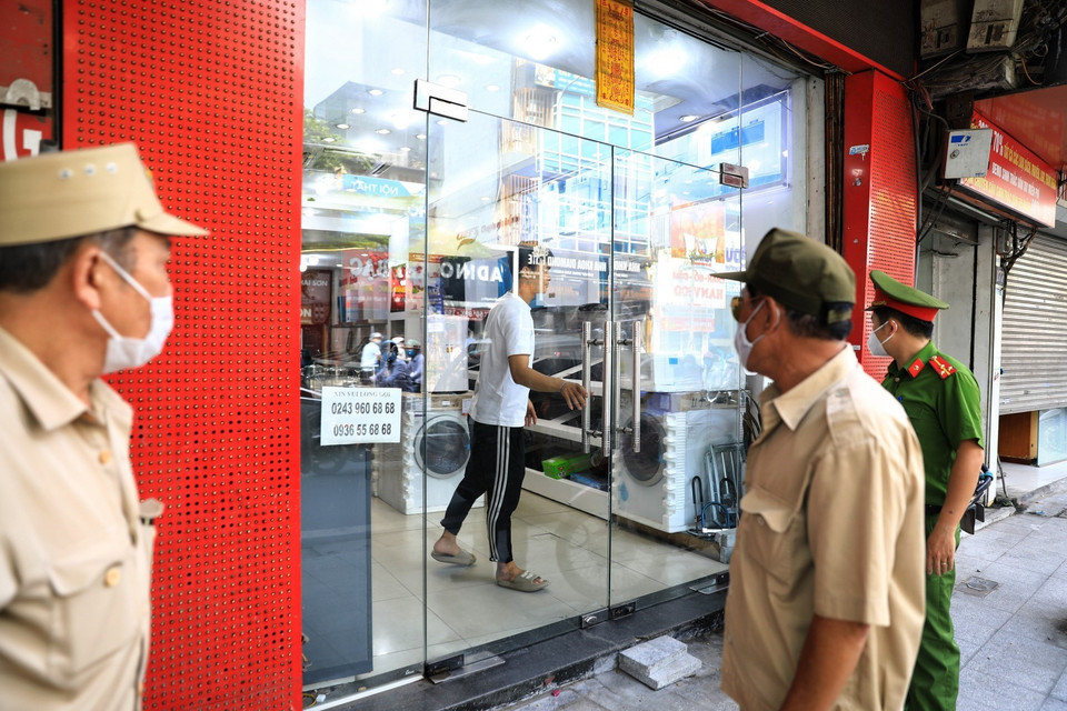 Lực lượng chức năng phường Ô Chợ Dừa, quận Đống Đa gọi loa yêu cầu các cửa hàng điện tử trên phố Nguyễn Lương Bằng đóng cửa. (Ảnh: Thành Đạt/TTXVN)