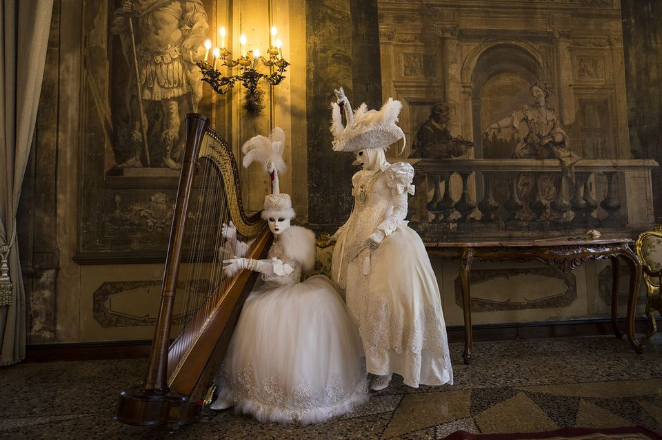 Hai người đeo mặt nạ hóa trang và mặc trang phục truyền bên chiếc đàn trong cung điện tại lễ hội Carnival ở Venice, Italy. (Nguồn: NatGeo)