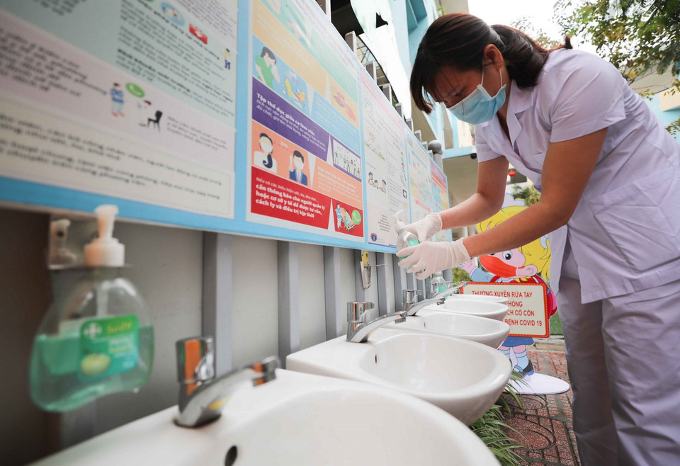 Nhân viên y tế trường mầm non Thịnh Liệt (quận Hoàng Mai (Hà Nội)) chuẩn bị dung dịch rửa tay đầy đủ để trẻ có thể thường xuyên rửa tay khi vào lớp. (Ảnh: Thanh Tùng/TTXVN)