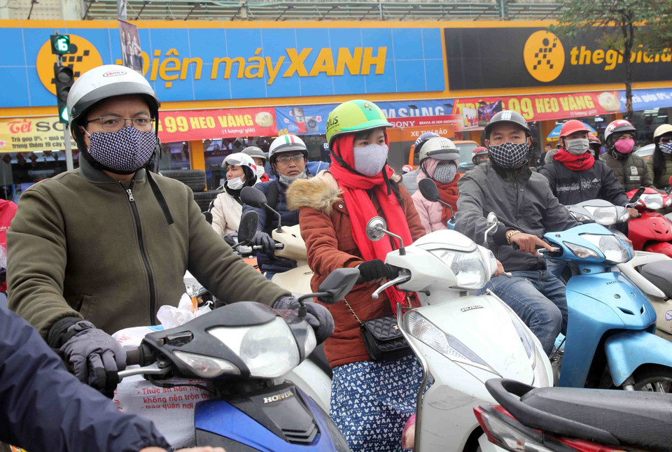 Người dân tại Hà Nội dạo chơi trên phố đi bộ Hồ Hoàn Kiếm đều trang bị cho mình quần áo ấm, quấn khăn, đeo khẩu trang… để chống lại thời tiết lạnh buốt. (Ảnh: Quang Quyết/TTXVN)