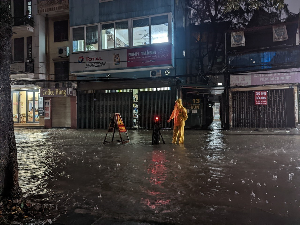 Công nhân Công ty Thoát nước Hà Nội ứng trực, cảnh báo khu vực ngập. (Ảnh: Mạnh Khánh/TTXVN)