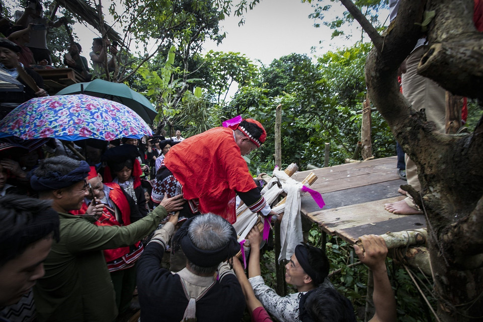 Thầy cúng bước lên bậc thang làm bằng các lưỡi dao quắm đặt chéo nhau lên ngũ đài để cúng giải hạn, xóa điều xấu, đón điều tốt về cho dòng họ. (Ảnh: Trọng Đạt/TTXVN)