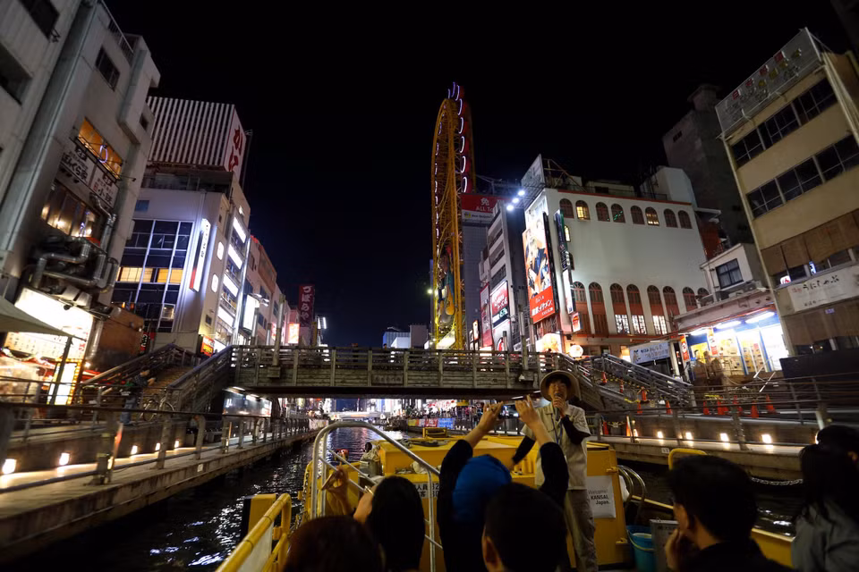Du khách đi thuyền trên sông Dotonbori ngắm cảnh hai bên bờ sông khi thành phố lên đèn. (Ảnh: Huy Hùng/TTXVN)