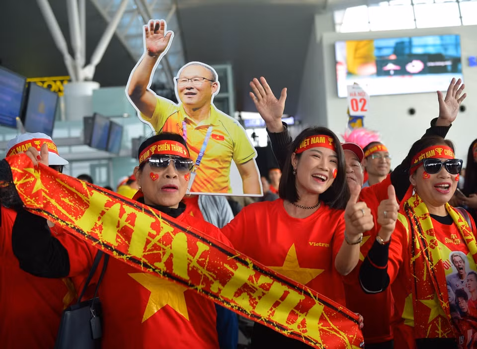 Cổ động viên nhuốm màu đỏ trên sân bay quốc tế Nội Bài. (Ảnh: CTV/Vietnam+)