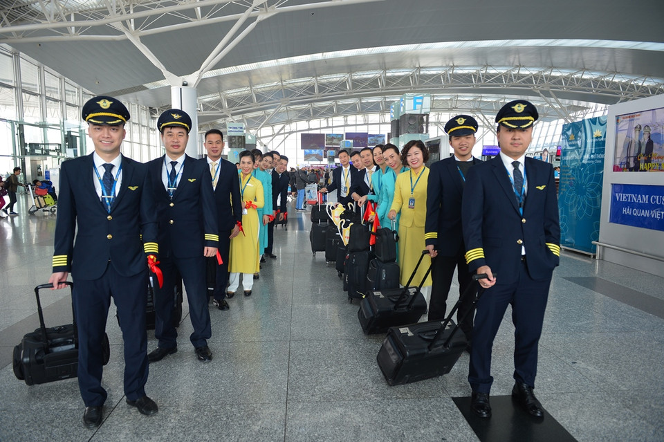 Phi hành đoàn Vietnam Airlines với băng rôn đeo tay và cờ Tổ quốc trên hành trình chở cổ động viên sang Philippines. (Ảnh: CTV/Vietnam+)