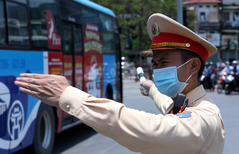 Trung úy Nguyễn Ngọc Tú (Đội cảnh sát giao thông số 4) phân luồng, điều tiết giao thông tại ngã tư Đại Cồ Việt-Giải phóng dưới nhiệt độ nắng nóng lên tới 40 độ C. (Ảnh: Phạm Kiên/TTXVN)