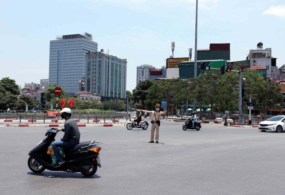 Trung úy Nguyễn Ngọc Tú (Đội cảnh sát giao thông số 4) phân luồng, điều tiết giao thông tại ngã tư Đại Cồ Việt-Giải phóng dưới nhiệt độ nắng nóng lên tới 40 độ C. (Ảnh: Phạm Kiên/TTXVN)
