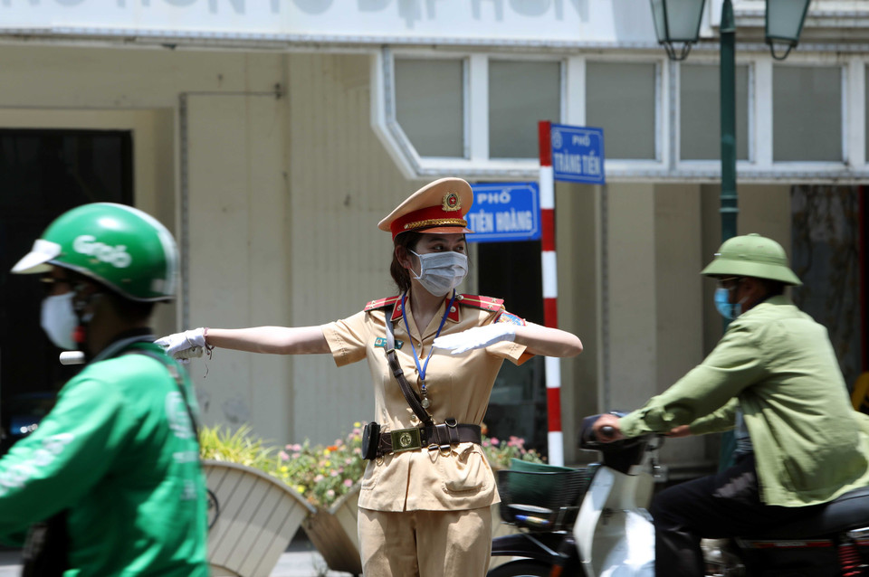 Trung úy Nguyễn Thị Thùy Dung, nữ chiến sỹ của Đội cảnh sát giao thông số 1 làm nhiệm vụ phân luồng điều tiết giao thông tại ngã tư Đinh Tiên Hoàng-Tràng Tiền dưới trời nắng nóng. (Ảnh: Phạm Kiên/TTXVN)