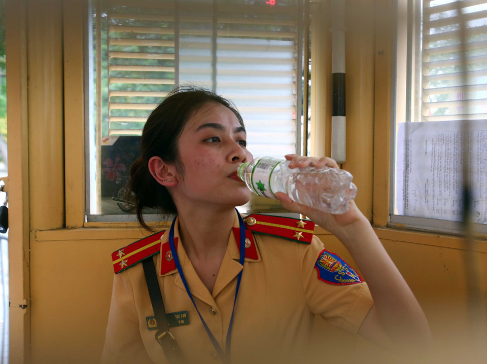 Do nắng nóng quá gay gắt, cứ khoảng 30 phút, Trung úy Nguyễn Thị Thùy Dung, nữ chiến sỹ của Đội cảnh sát giao thông số 1 lại vào bốt trực để tranh thủ uống nước. (Ảnh: Phạm Kiên/TTXVN)
