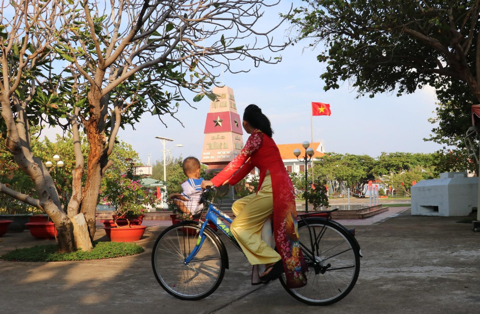Công dân nhí Lâm Nhật Kiến Huy (18 tháng tuổi) được mẹ là chị Nguyễn Thị Phương Dung chở trên xe đạp nhìn qua cột mốc trên đảo Trường Sa Lớn. (Ảnh: Sỹ Tuyên/TTXVN)