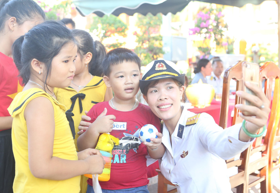 Thượng úy Hải quân Trần Thị Thủy, người con gái duy nhất của liệt sỹ, Anh hùng lực lượng vũ trang nhân dân Trần Văn Phương chụp ảnh cùng các công dân nhí đảo Sinh Tồn. (Ảnh: Sỹ Tuyên/TTXVN)