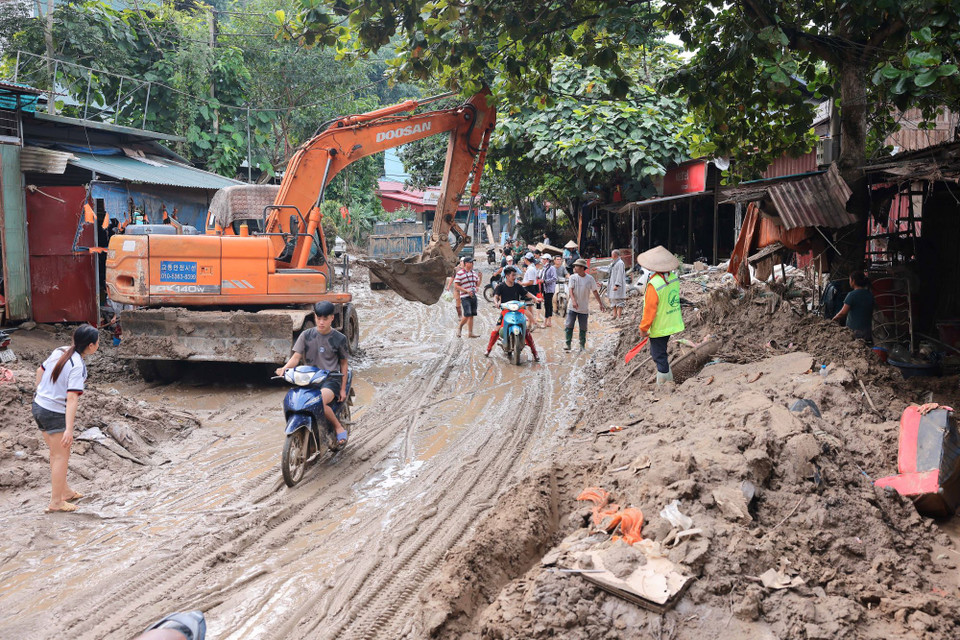 Các lực lượng chức năng đang tích cực dọn dẹp bùn đất để các phương tiện lưu thông trên Quốc lộ 70 an toàn. (Ảnh: Hoàng Hiếu/TTXVN)