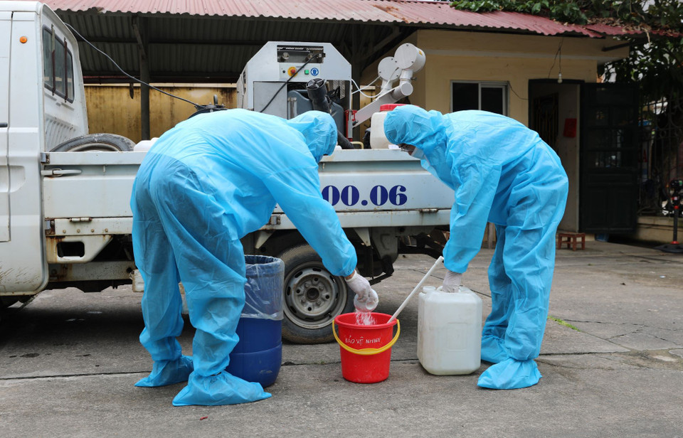 Cán bộ Trung tâm Kiểm soát bệnh tật tỉnh Yên Bái pha Cloramin B phun khử khuẩn môi trường. (Ảnh: Tuấn Anh/TTXVN)