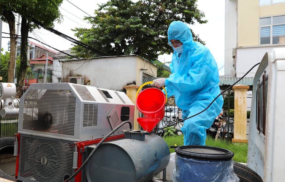 Cán bộ Trung tâm Kiểm soát bệnh tật tỉnh Yên Bái pha Cloramin B phun khử khuẩn môi trường. (Ảnh: Tuấn Anh/TTXVN)