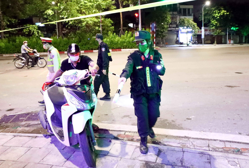 Trung úy Thanh kiểm tra giấy tờ đi đường những người tham gia giao thông để phòng, chống dịch. (Ảnh: Phạm Kiên/TTXVN)