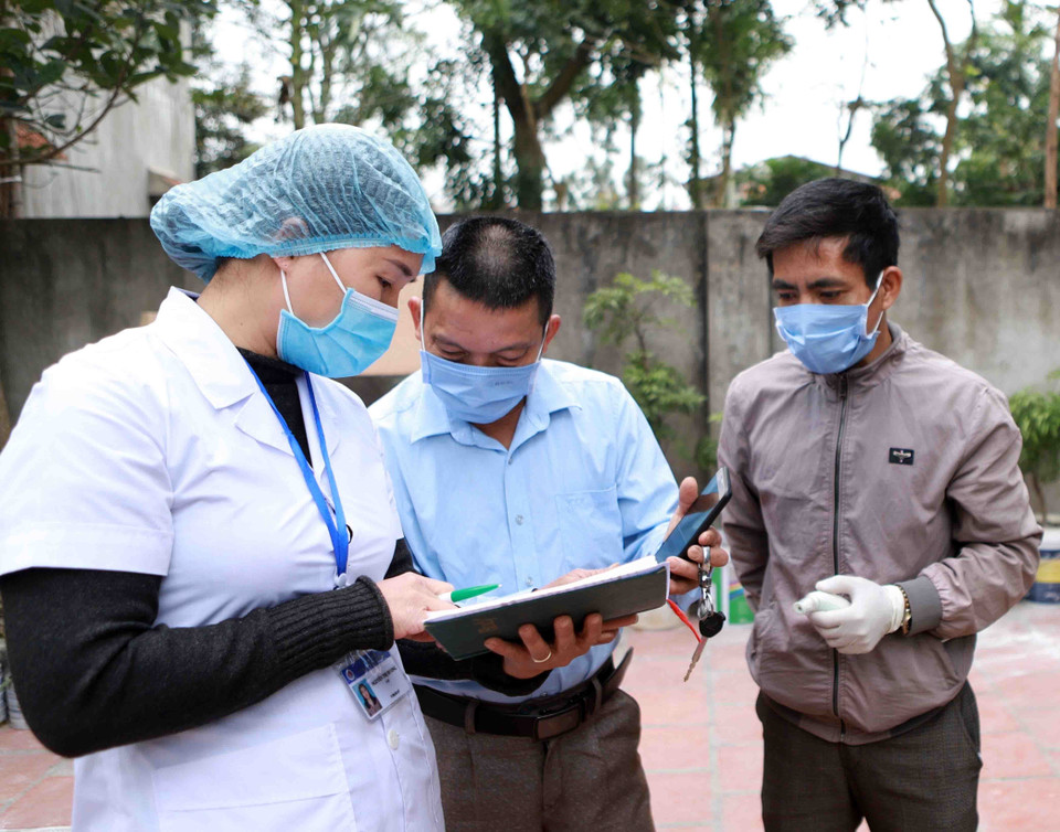 Trưởng thôn thôn Lương Câu Nguyễn Mạnh Dương (thứ 2 từ trái sang) cùng cán bộ Trung tâm kiểm soát bệnh tật Vĩnh Phúc (áo trắng) kiểm tra số liệu theo dõi sức khỏe của người dân. (Ảnh: Hoàng Hùng/TTXVN)