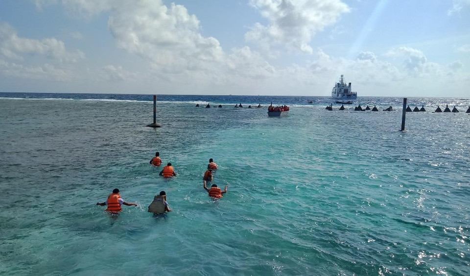 Do nước biển xuống thấp, các chiến sỹ tại đảo Sinh Tồn Đông đã xuống biển đẩy xuồng đưa đoàn đại biểu ra khỏi bãi san hô để lên tàu tiếp tục hải trình đi thăm các đảo. (Ảnh: Hùng Võ/Vietnam+)