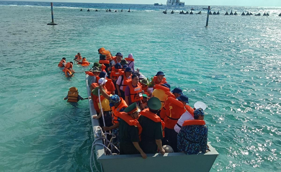 Các chiến sỹ kéo xuồng đưa đoàn đại biểu ra khỏi bãi san hô để lên tàu. (Ảnh: Hùng Võ/Vietnam+)